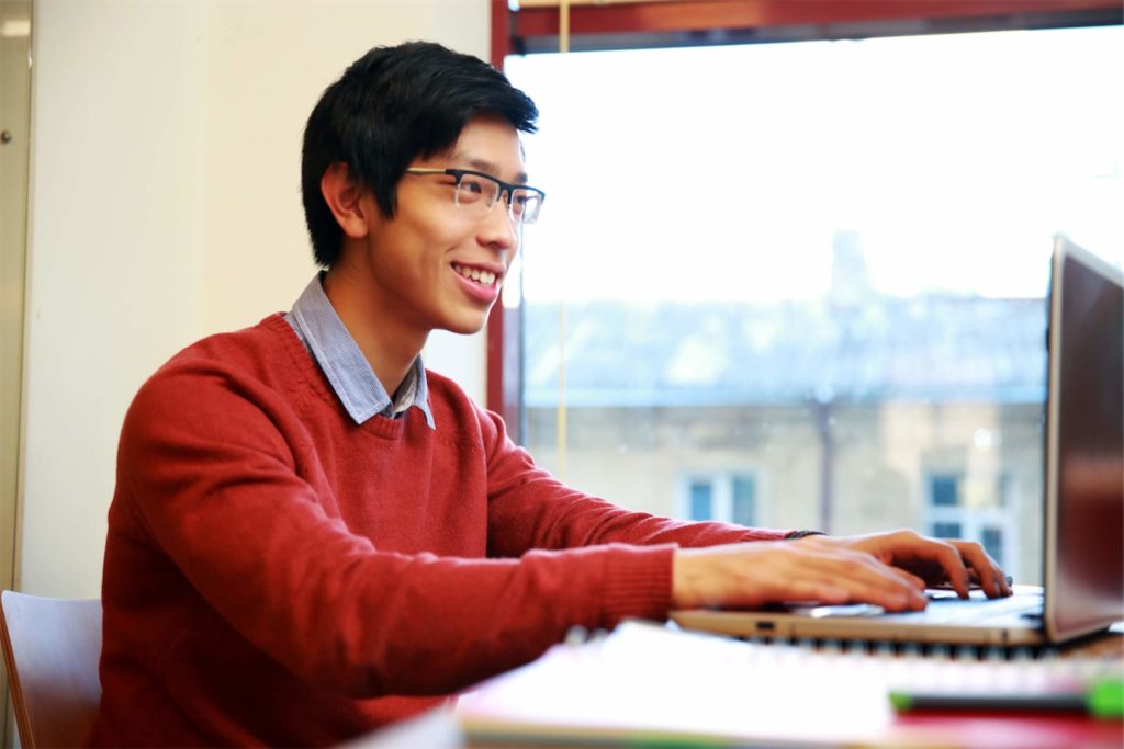 Smiling man in glasses working on laptop