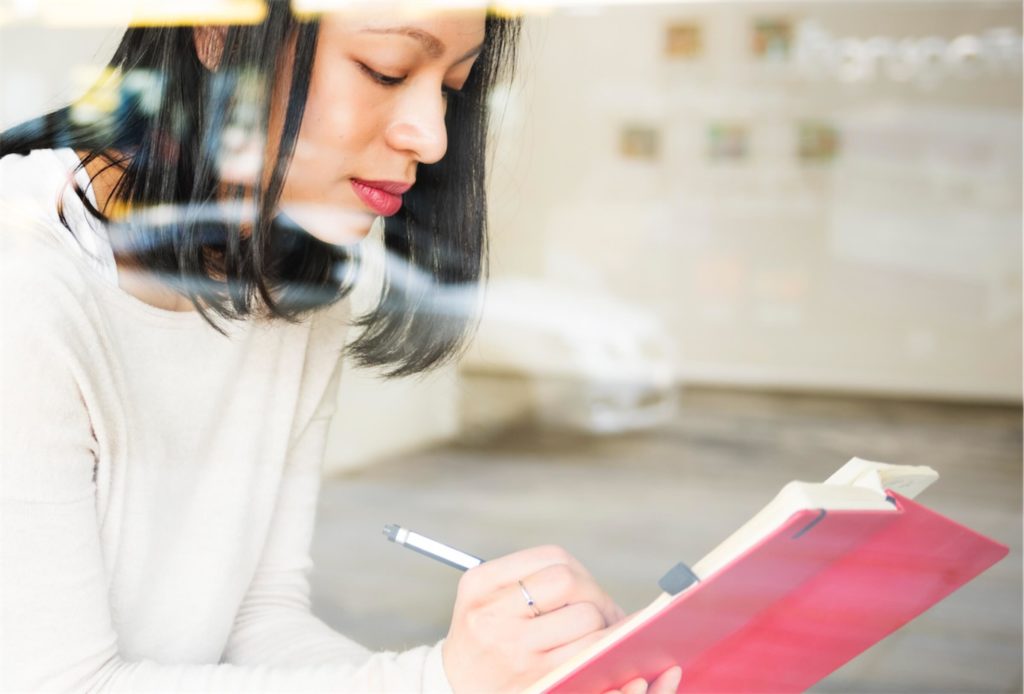 Woman taking down notes for her studies, which can be funded by a personal loan in Singapore