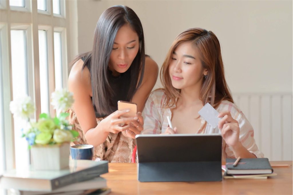 Women holding a card and use a smartphone to search for information