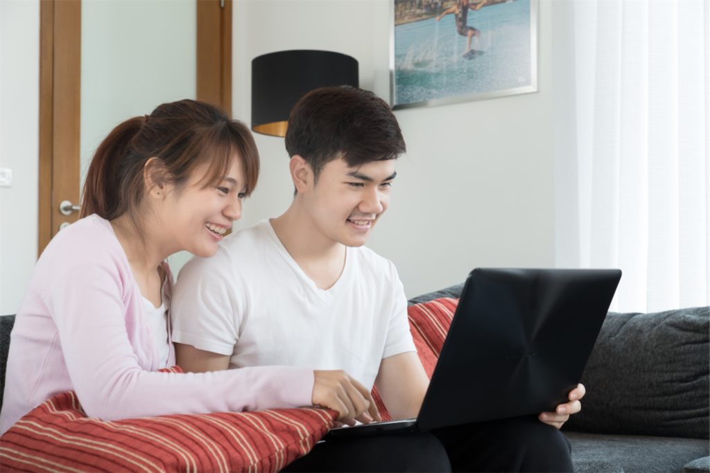 Happy couple applying for personal loan in singapore on a laptop with a licensed money lender