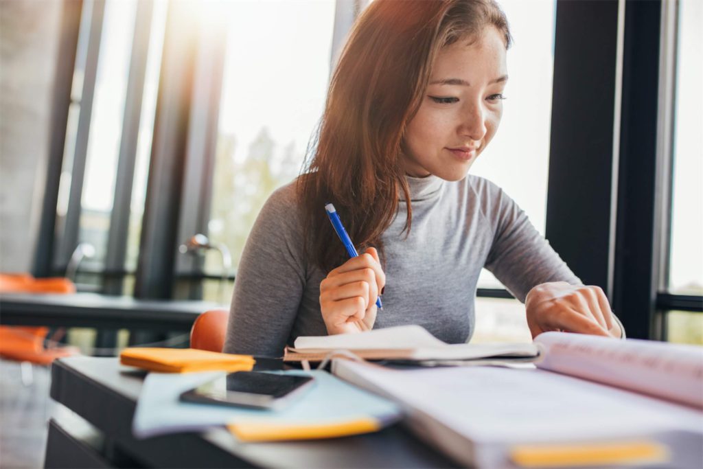 A woman studying in a library for a short-term course that’s paid with a personal loan in Singapore