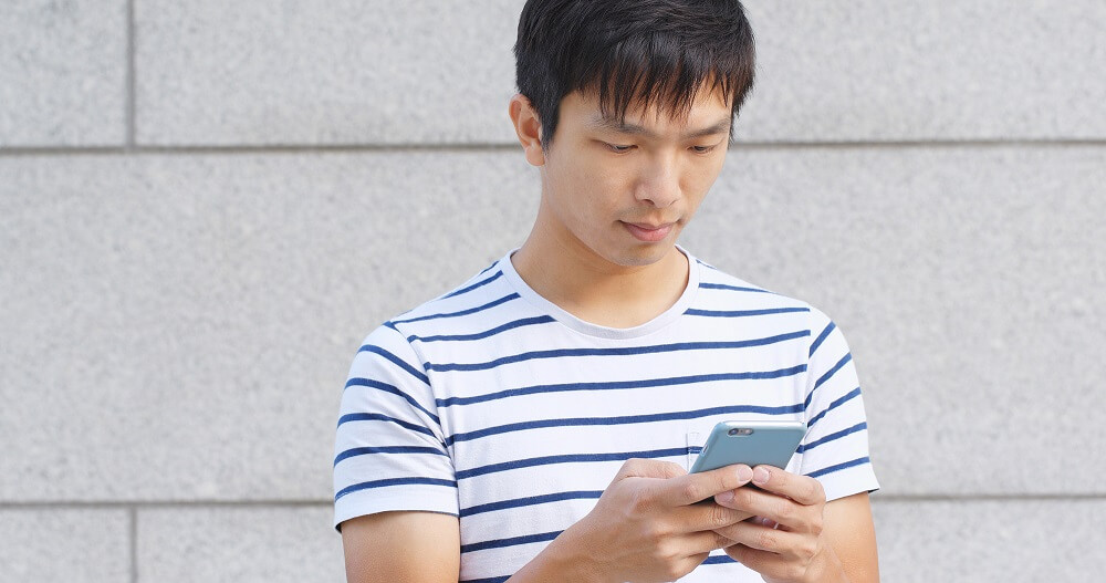 Man reading text message on phone from a loan shark in Singapore