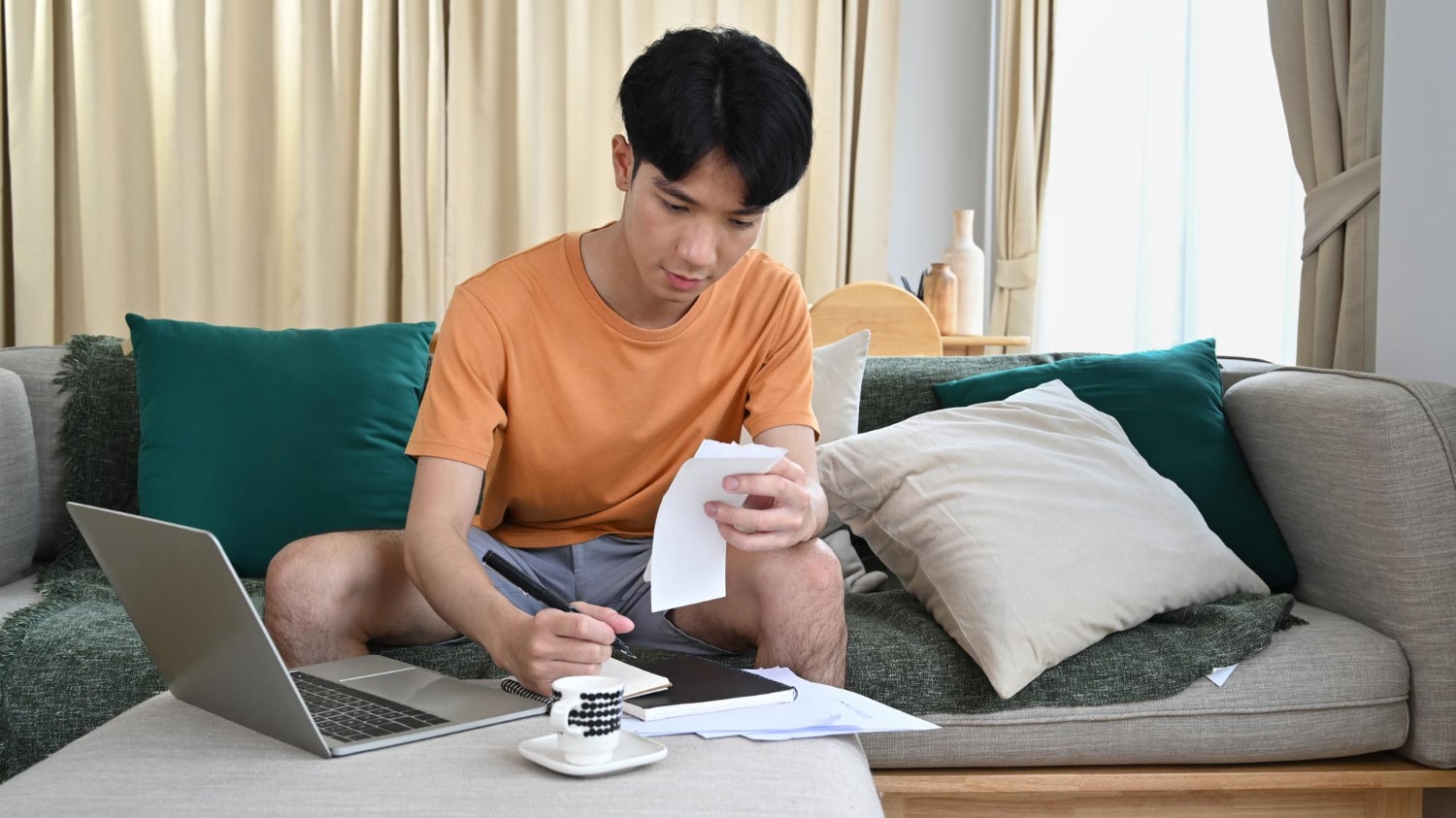 Man reviews bills and notes on the sofa